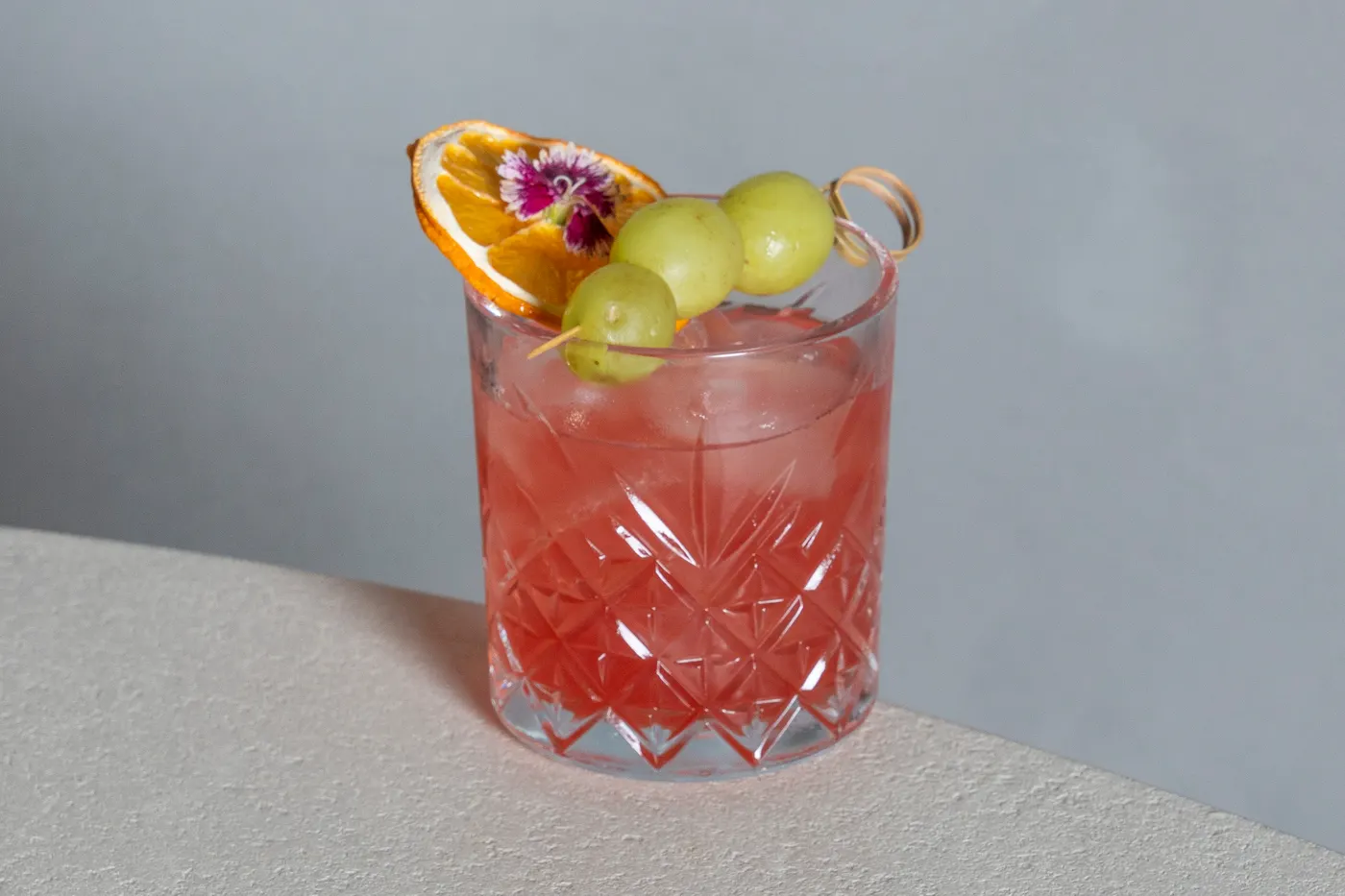 Cóctel rosado con uvas y flor comestible en Pauza La Cala de Mijas
